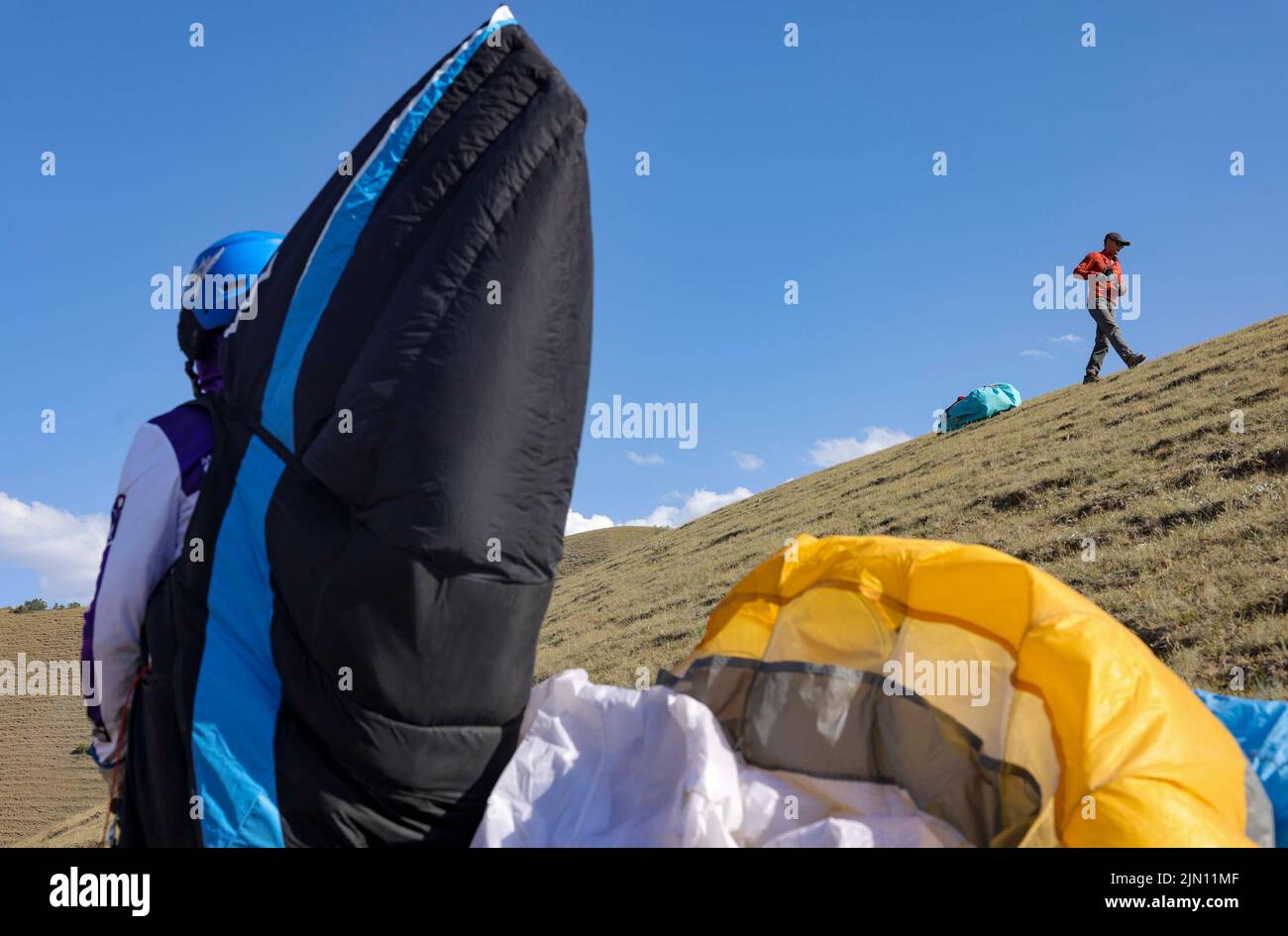 (220808) -- XINJIANG, Aug. 8, 2022 (Xinhua) -- Chen Ruifeng prepares before taking off in southern suburb of Urumqi, northwest China's Xinjiang Uygur Autonomous Region, June 11, 2022. Born in Xinjiang, 52-year-old Chen Ruifeng is a paragliding amateur. He says he feels like having his own wings when the paraglider opens. In 2016, Chen Ruifeng started to practice paragliding. Later on, he joined a local club and received his flying certificate after training. As an outdoor enthusiast, he also engages himself in trail running, mountaineering and ice climbing. In his opinions, the unique terrain Stock Photo