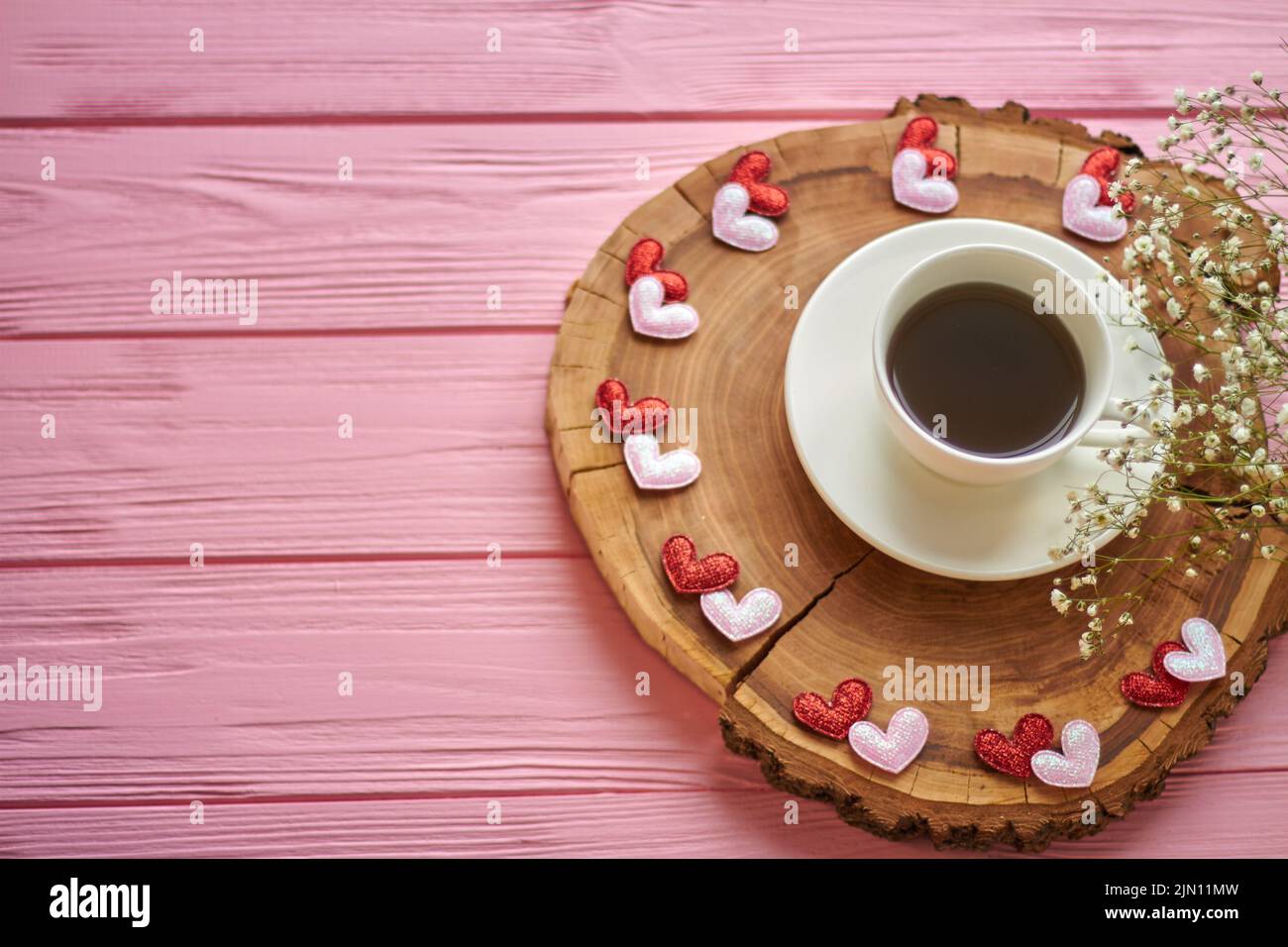 Top view coffee cup with hearts and flowers. Round rustic wooden board. Stock Photo