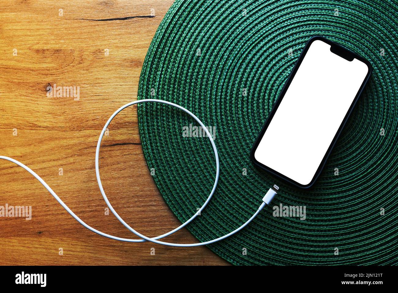 Smartphone with blank mockup screen and mobile charger cable on the table, top view copy space Stock Photo