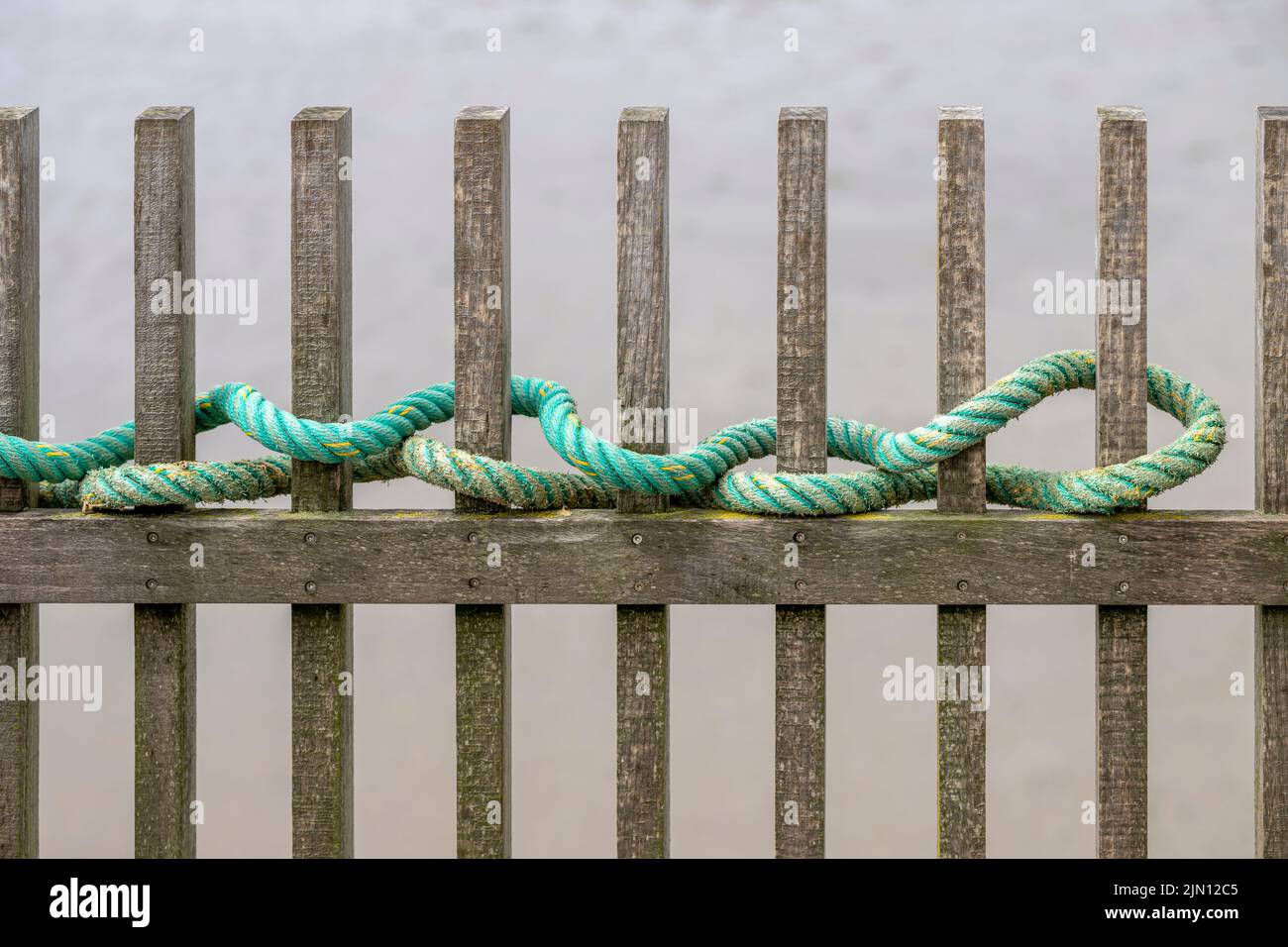 Weathered wooden fence with green rope woven through it Stock Photo Alamy