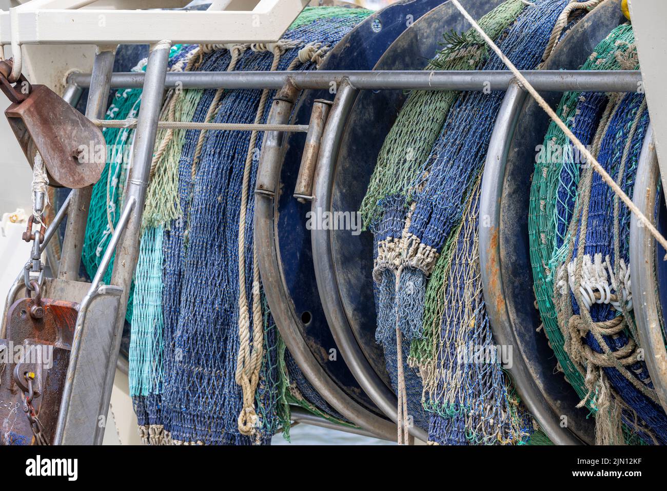 Rolled up blue and green fishing nets on a stern of a fishing boat in a ...