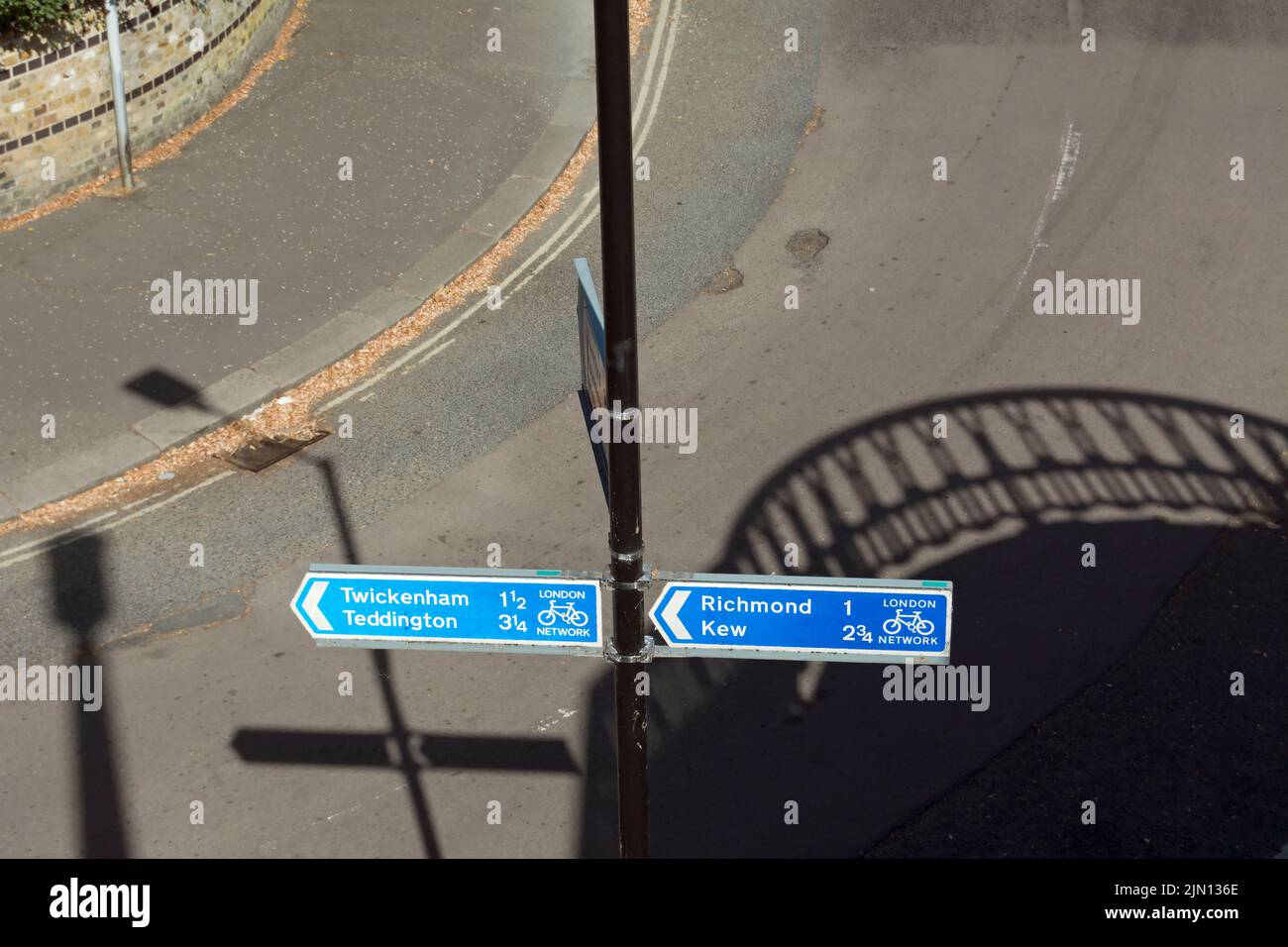 with the shadow of twickenham bridge in the background, cycle route direction signs for twickenham, teddington, richmond and kew, london, england Stock Photo