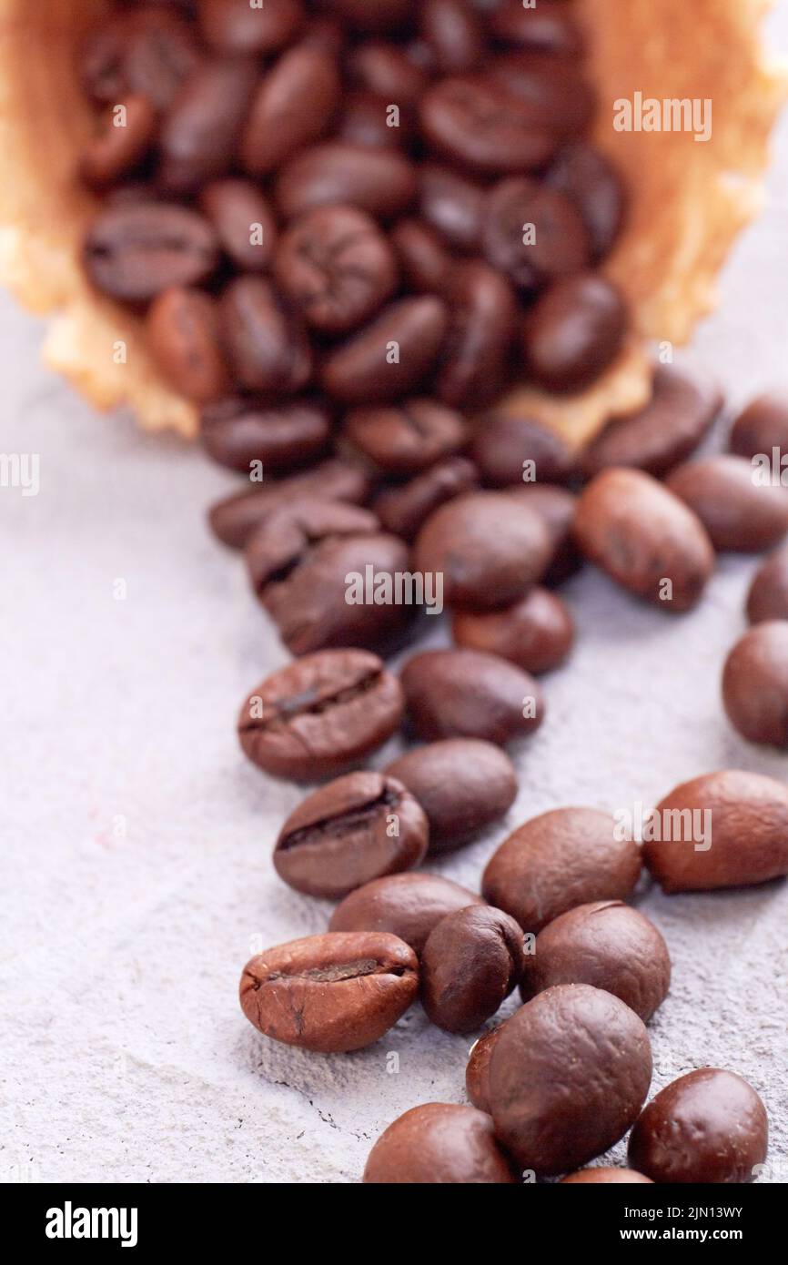 Vertical shot close up of coffee beans. Waffle ice cream cone with spilled grains. Stock Photo