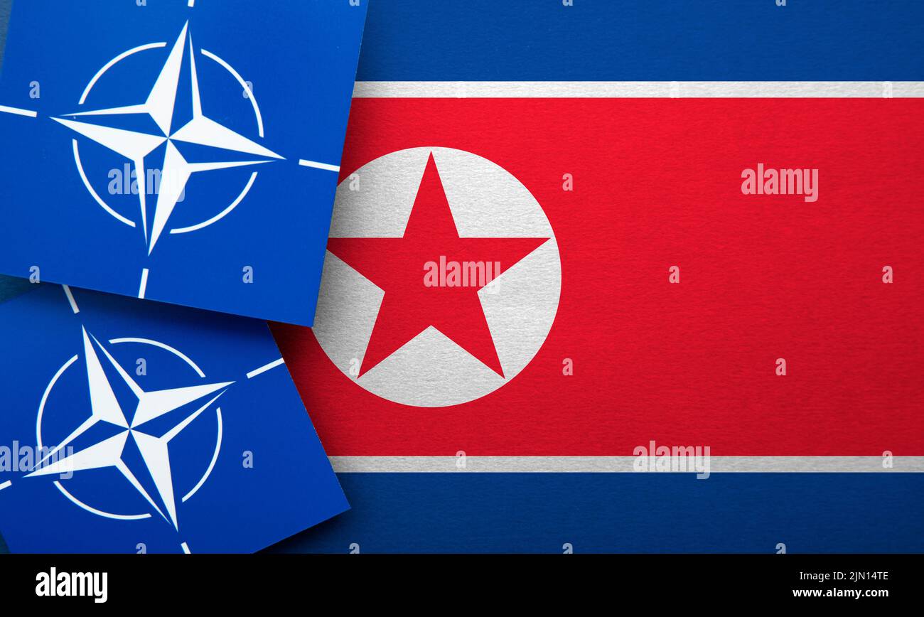 LONDON, UK - August 2022: NATO North Atlantic Treaty Organization military alliance logo on a North Korea flag Stock Photo