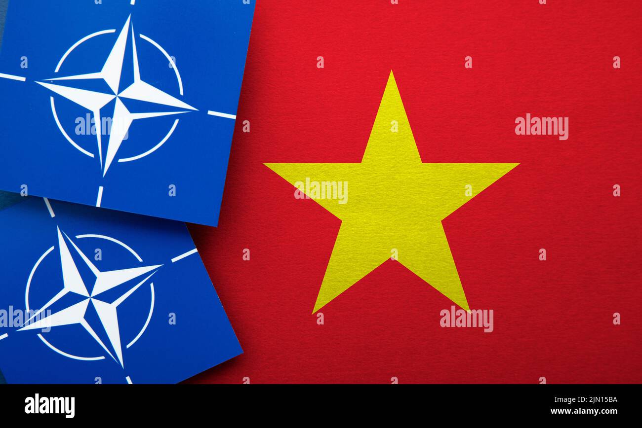 LONDON, UK - August 2022: NATO North Atlantic Treaty Organization military alliance logo on a Vietnam flag Stock Photo