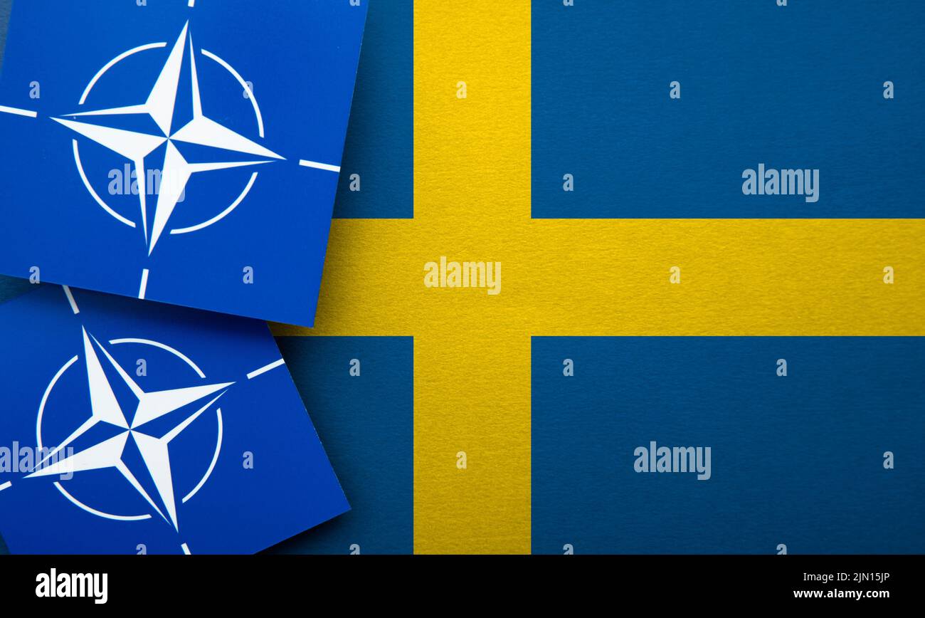 LONDON, UK - August 2022: NATO North Atlantic Treaty Organization military alliance logo on a Sweden flag Stock Photo