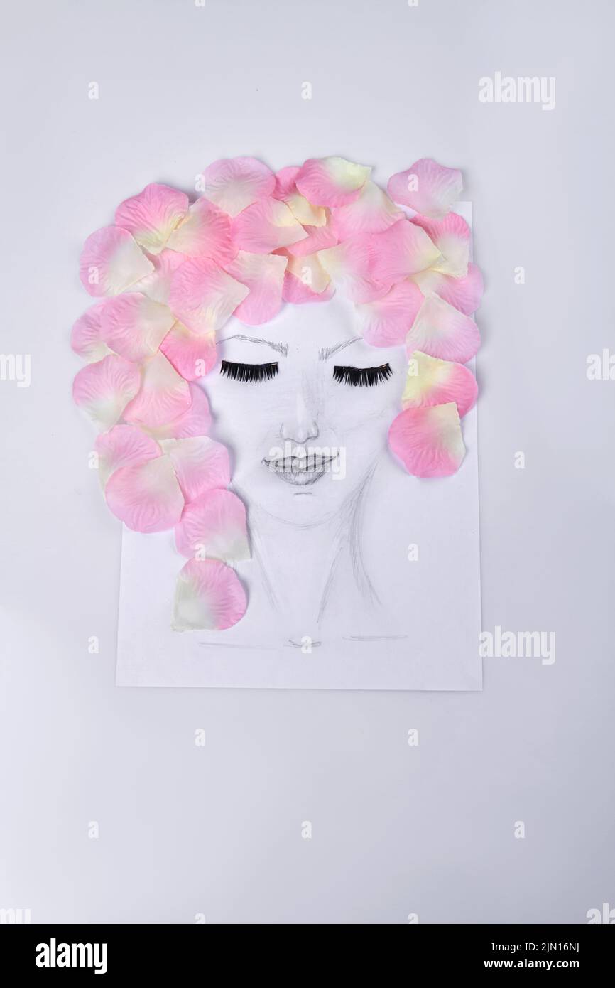 Hand drawn female face with pink petals represent her hair. Vertical shot portrait of woman with eyes closed on white surface. Stock Photo