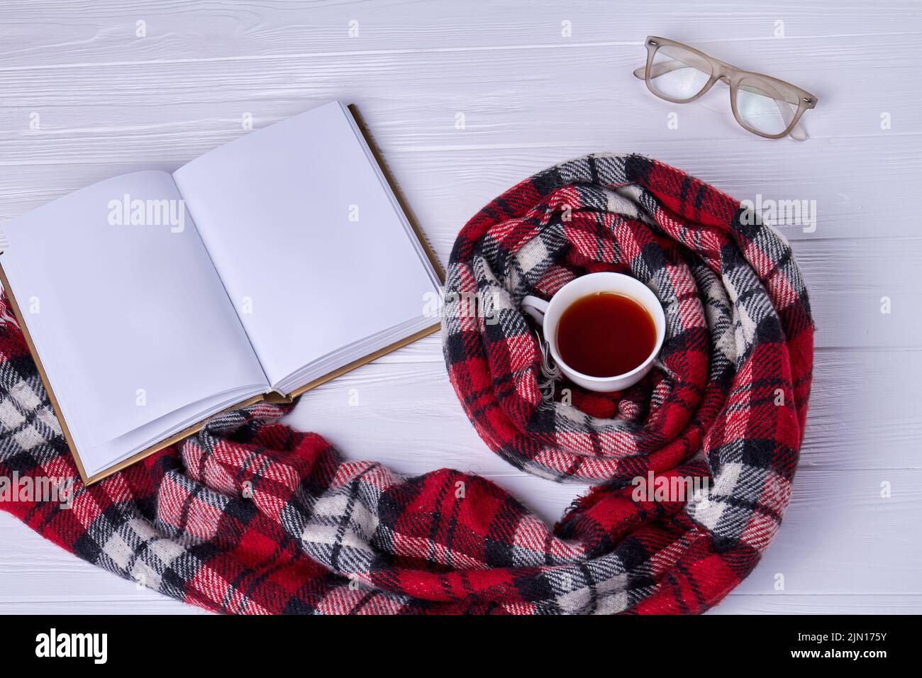 Top view cup of tea with scarf. Blank notebook with glasses. Stock Photo