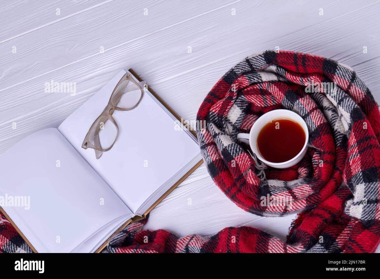 Top view cup of tea with scarf. Blank notebook with glasses. Stock Photo