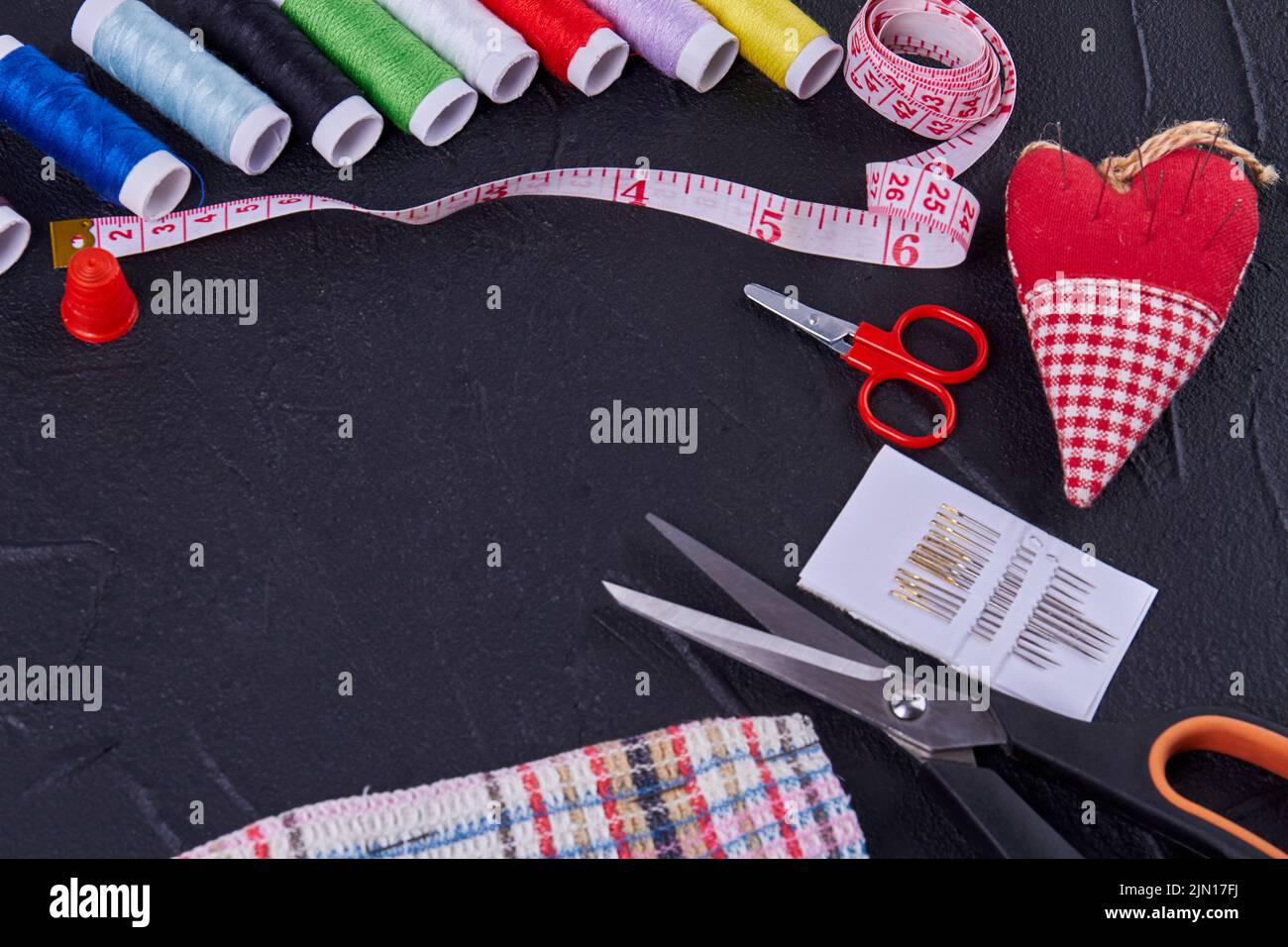 Top view sewing accessories with scissors and threads. Heart shaped needle pillow. Stock Photo