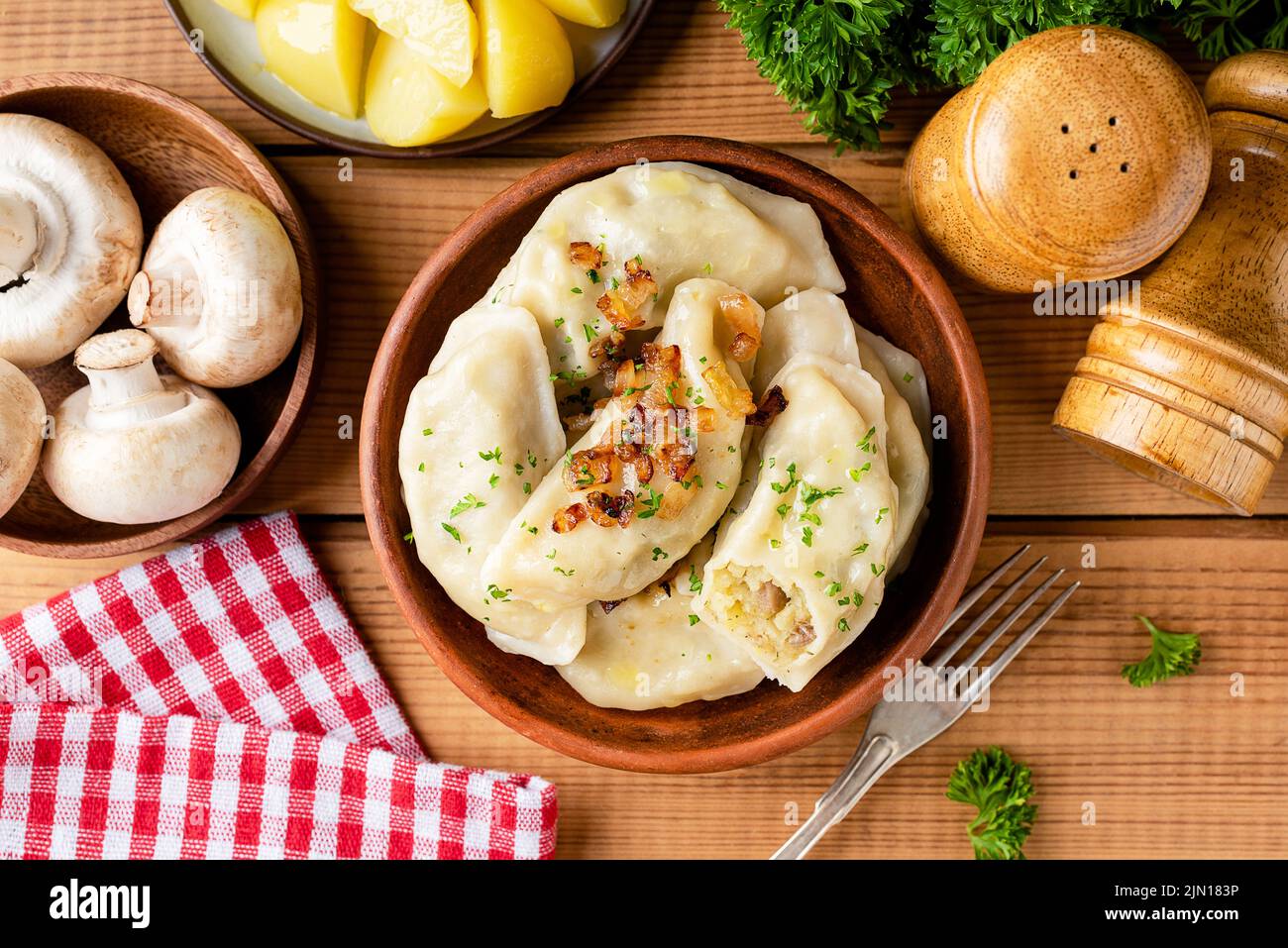 Pierogi, vareniky or potato dumplings in clay bowl on wooden table background, top view. Traditional Ukrainian cuisine food Stock Photo
