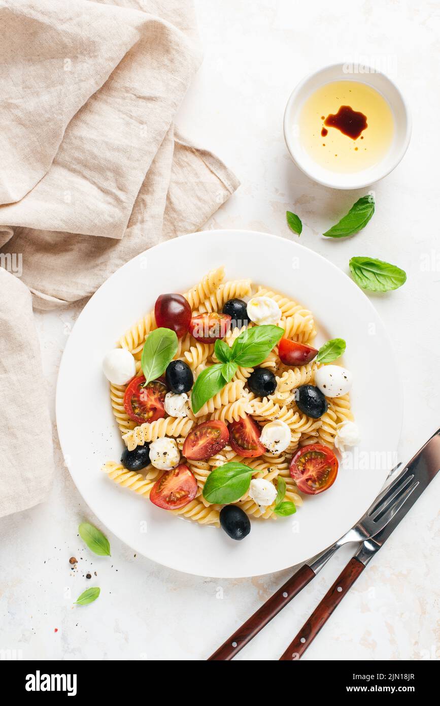 Cold fussili pasta salad with black olives, mozzarella cheese and cherry tomatoes, top view Stock Photo