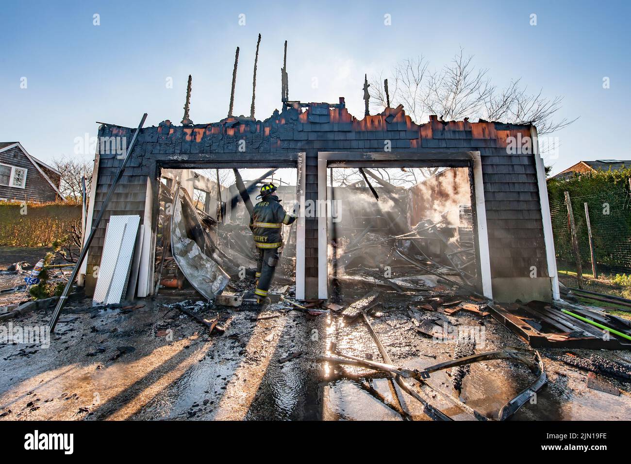 A firefighter surveys the remains after Bridgehampton firefighters wet down and overhauled the remains of a working garage fire at 354 Jobs Lane on Fr Stock Photo