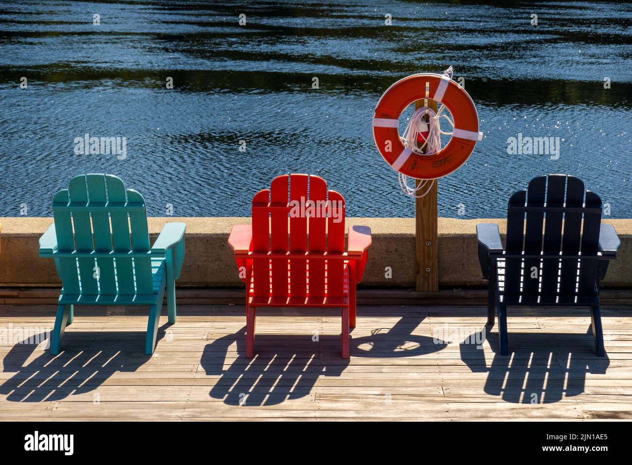 colorful Adirondack chairs along the Kennebec river in Hallowell Maine Stock Photo