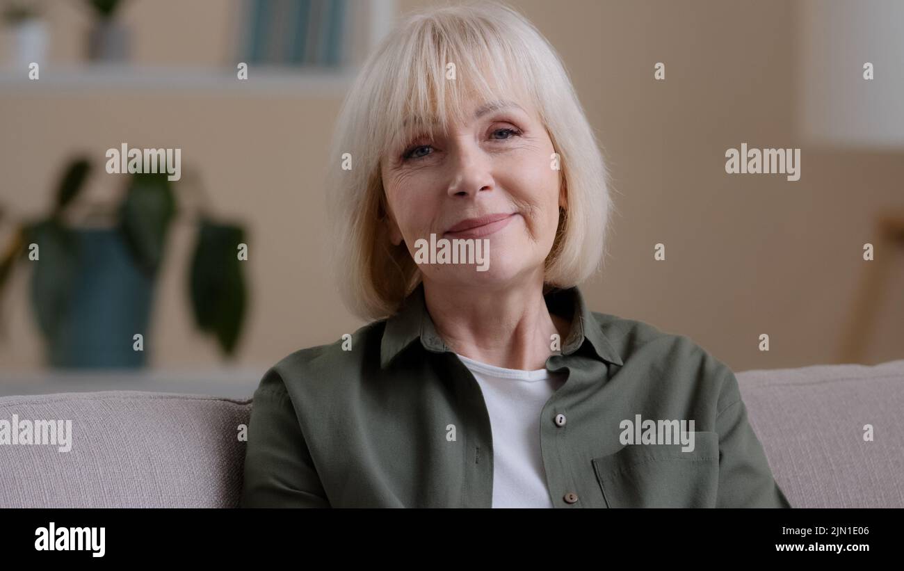 Web cam view close up happy friendly older 60s woman looking at camera talking distant remote conference calling video chat at home. Smiling senior Stock Photo