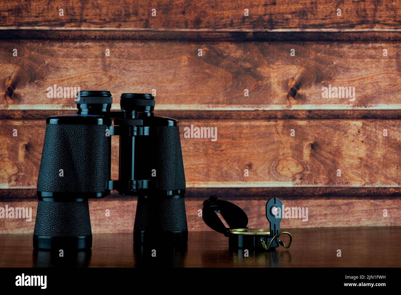 Compass and binoculars on a polished wooden shelf Stock Photo