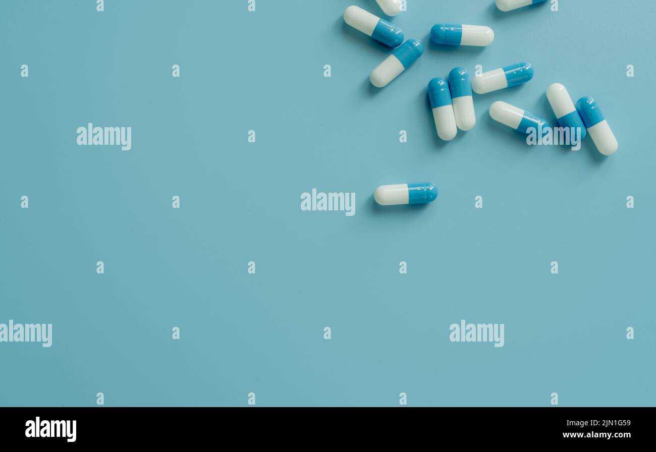 Top view blue-white antibiotic capsule pills on blue background. Prescription drug. Antibiotic drug resistance. Pharmaceutical industry. Pharmaceutic Stock Photo