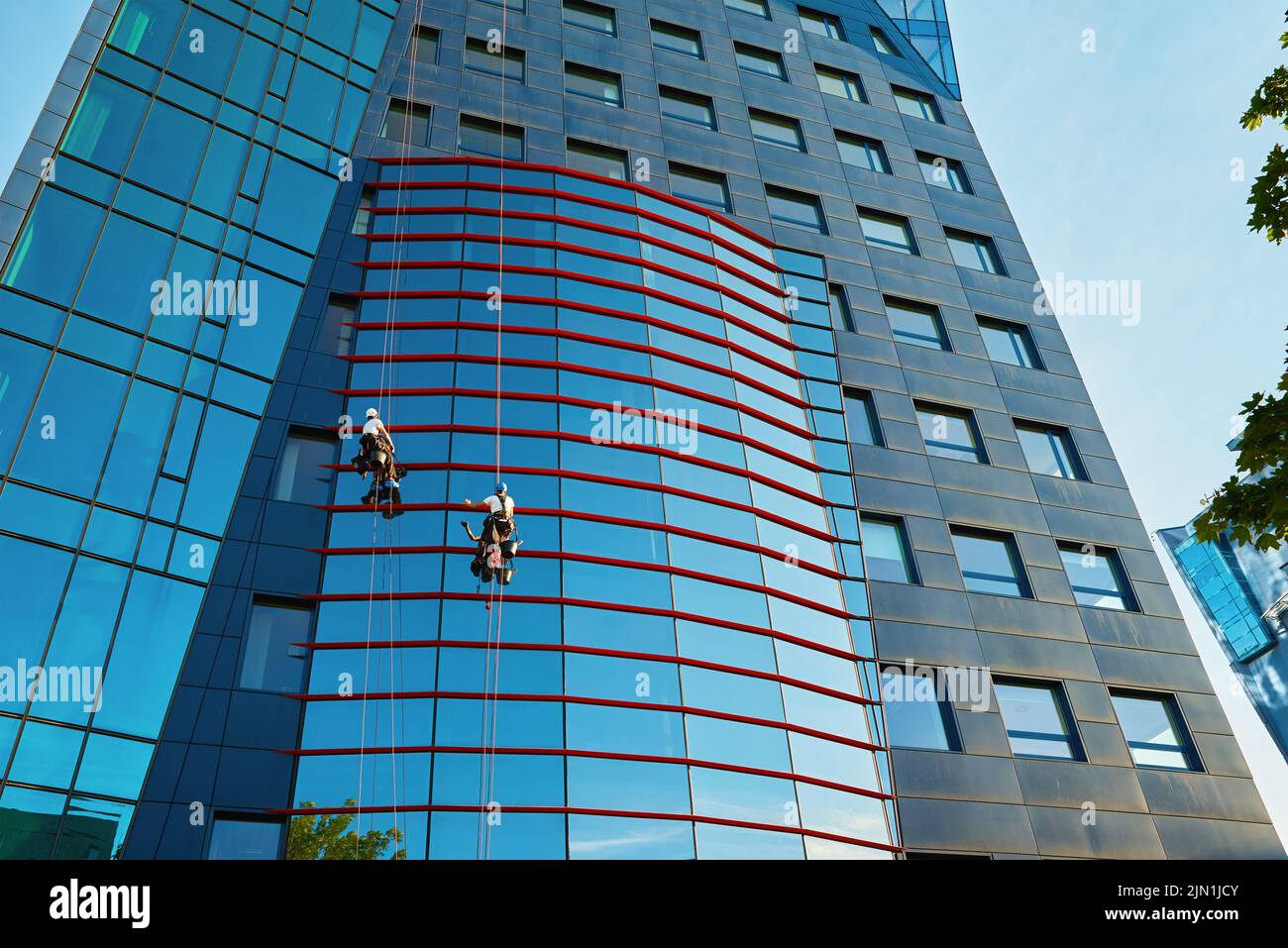 Two workers cleaning window in business center, Industrial alpinists washing exterior of