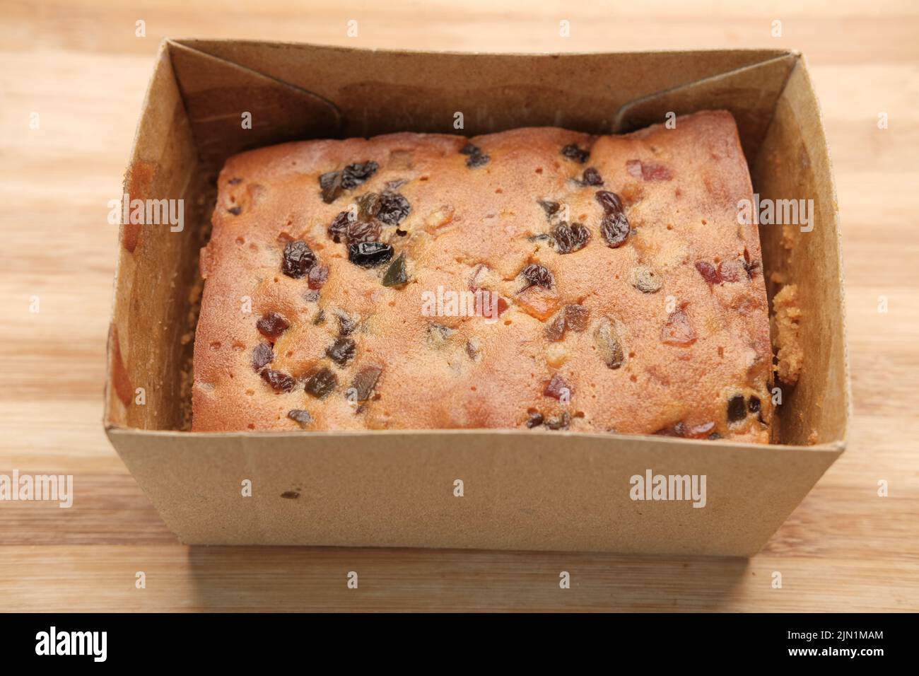 slice of bakery fruit cake in a paper packet on table  Stock Photo