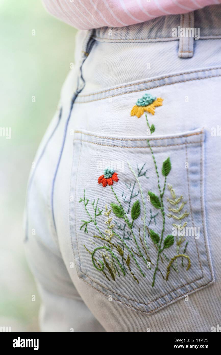 Parrot faded jeans with embroidered flower knee patches photographed on a  white background Stock Photo - Alamy