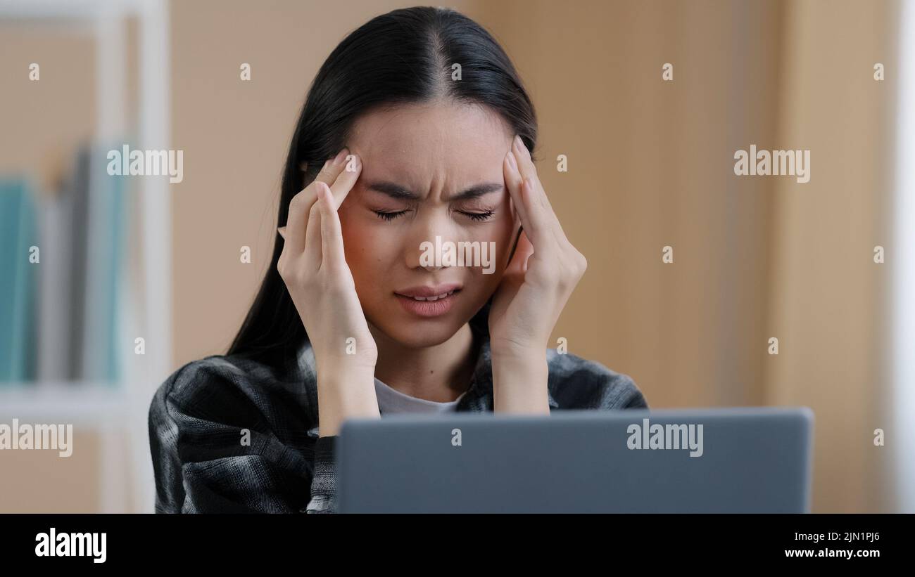 Unwell female Asian korean japanese chinese girl millennial business woman tired exhausted worker manager stressful student with laptop feeling tired Stock Photo