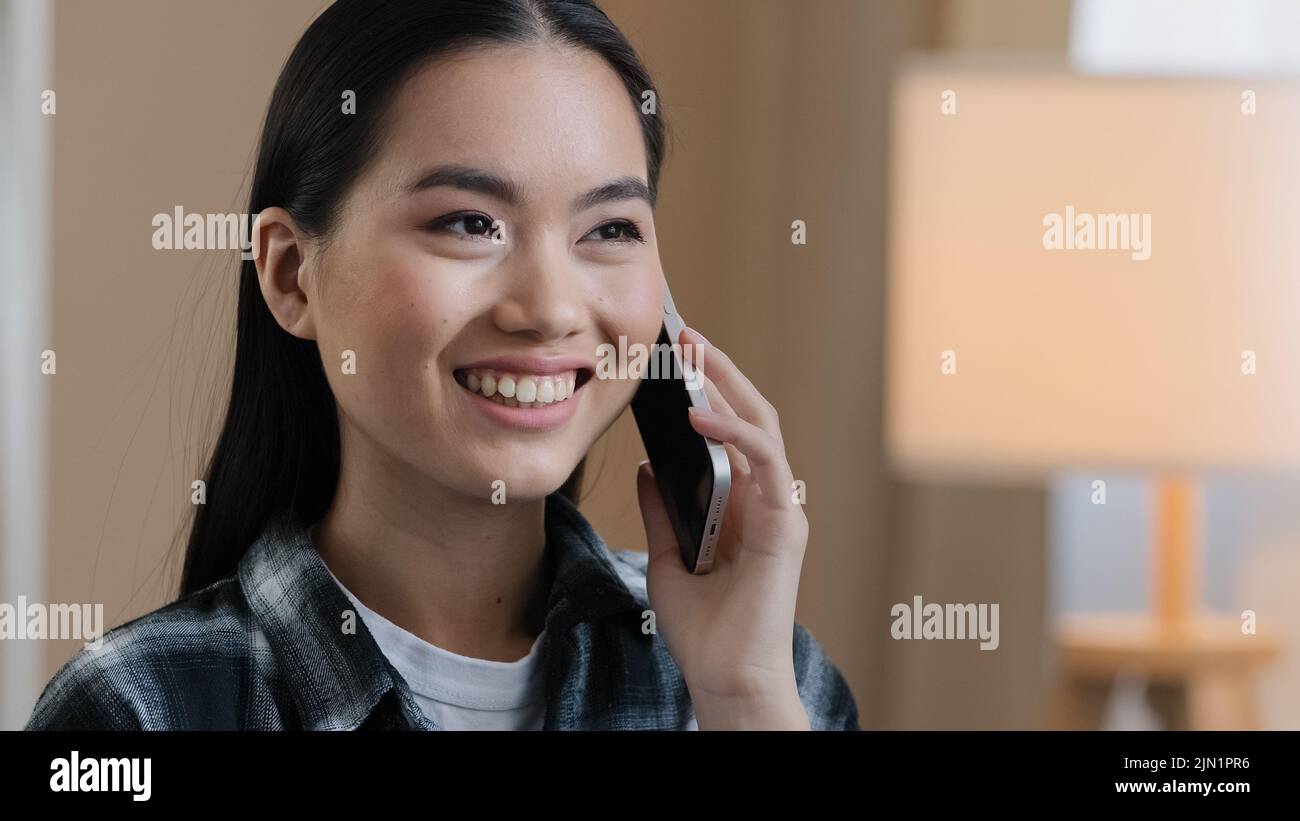 Asian girl answering phone call chatting with friends calling mobile phone laughing smiling friendly conversation remote chat communication portrait Stock Photo