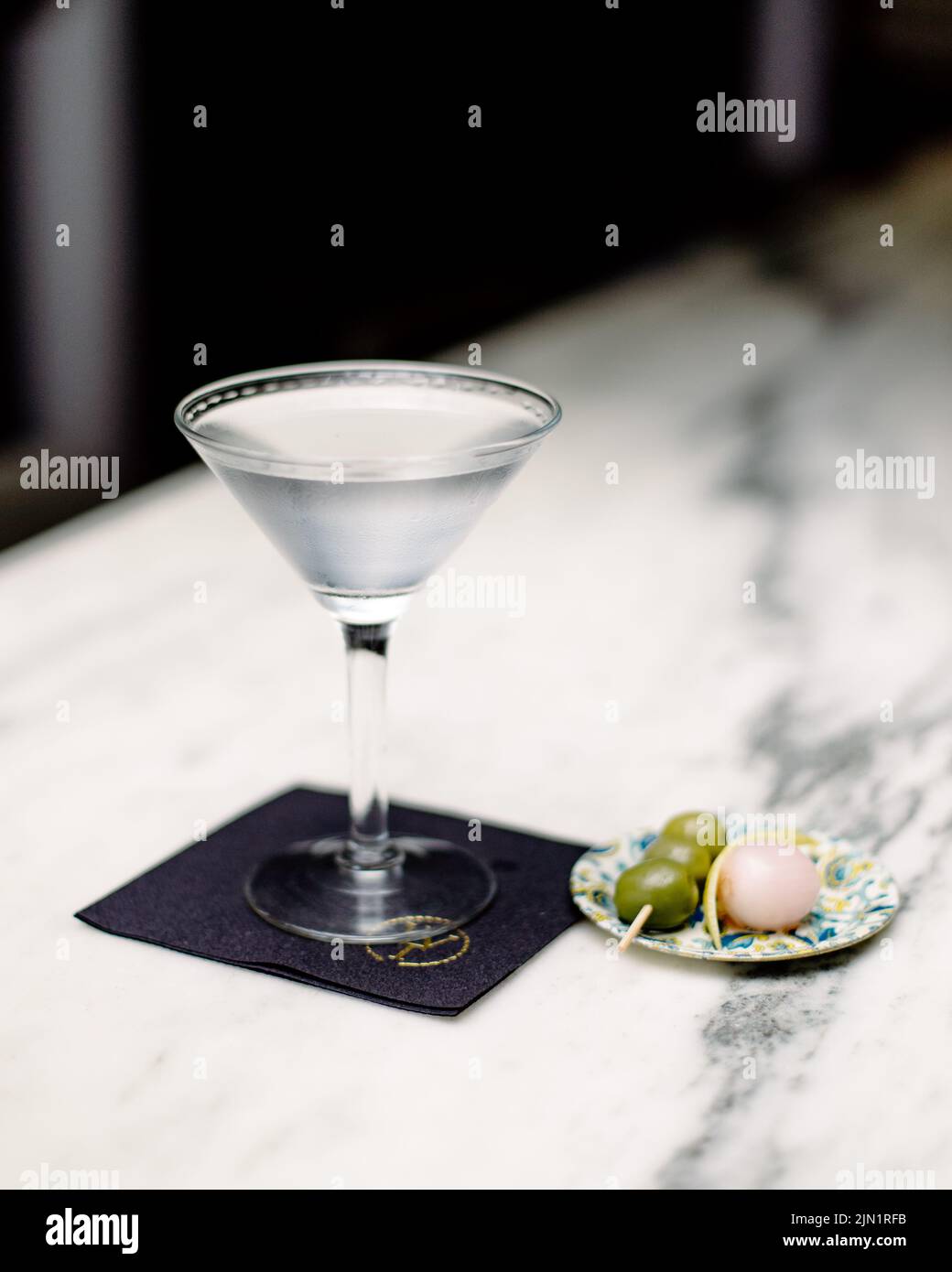 Ice cold martini sits on white marble bar Stock Photo
