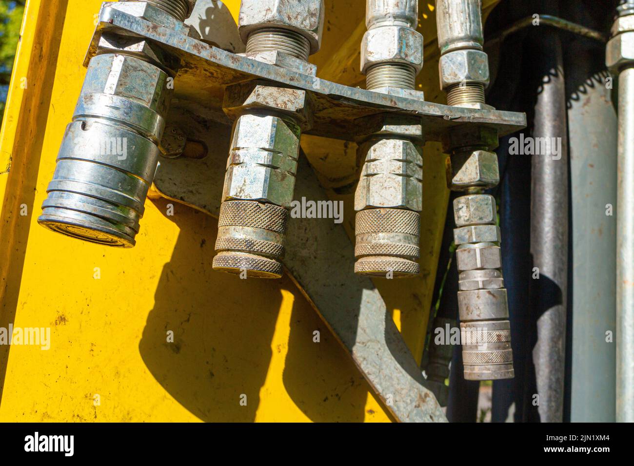 Various adapters for hydraulic hoses on the bucket arm of a wheel loader for attaching different types of buckets Stock Photo