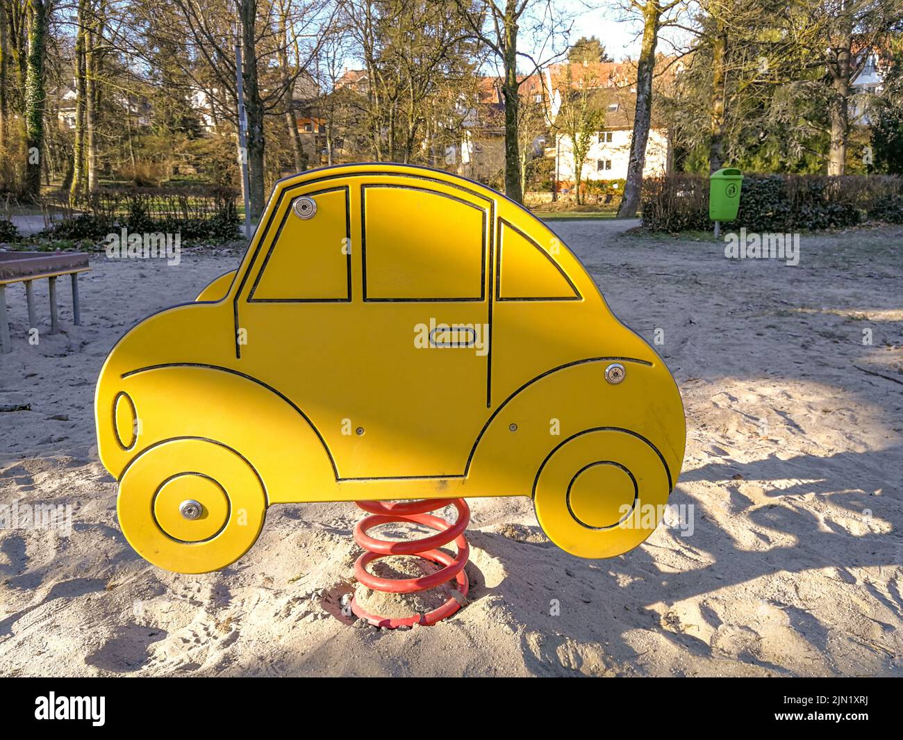 Spring seesaw in the shape of a stylized car on an empty children's playground with a sandy floor Stock Photo