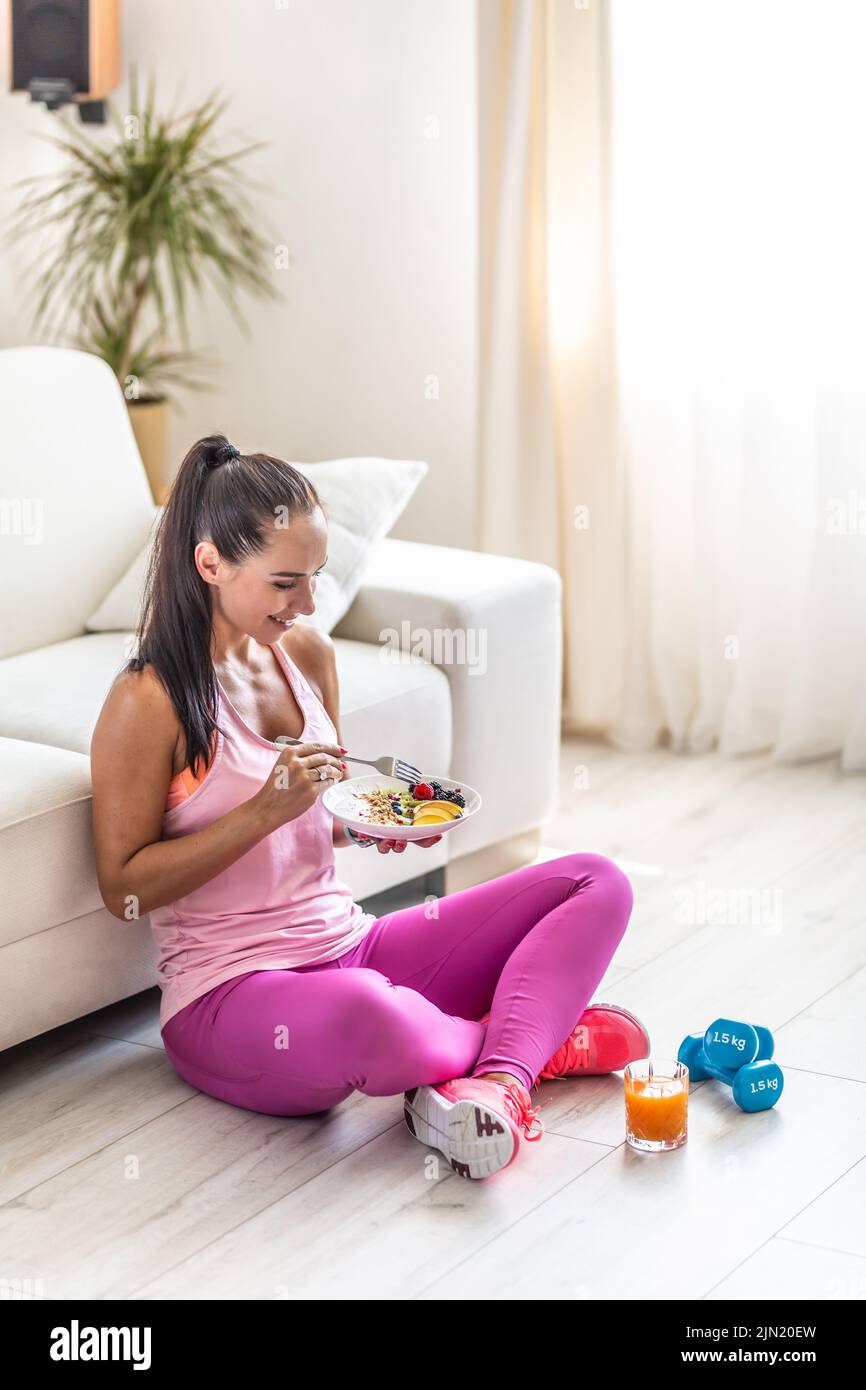 Sporty young woman eating a oatmeal with berries and fruits after a workout. Stock Photo