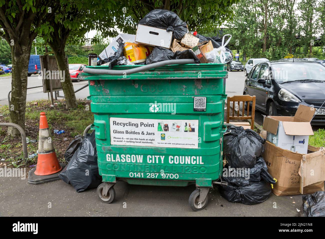 Overflowing rubbish bin and black plastic bags on a pavement waiting to be cleared, Glasgow, Scotland, UK Stock Photo
