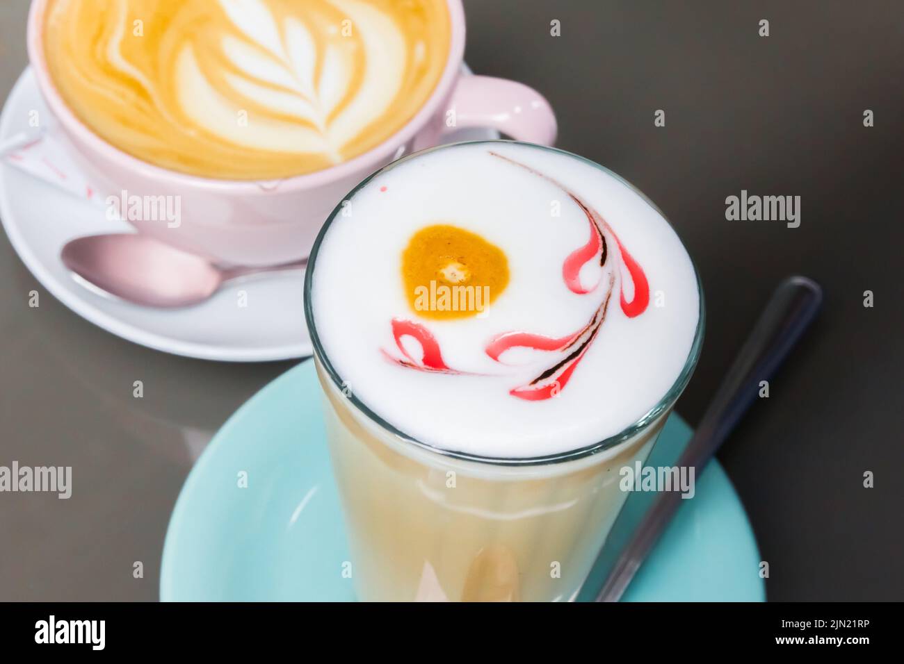 Glass of latte macchiato and a cup of cappuccino with decorated foam Stock Photo