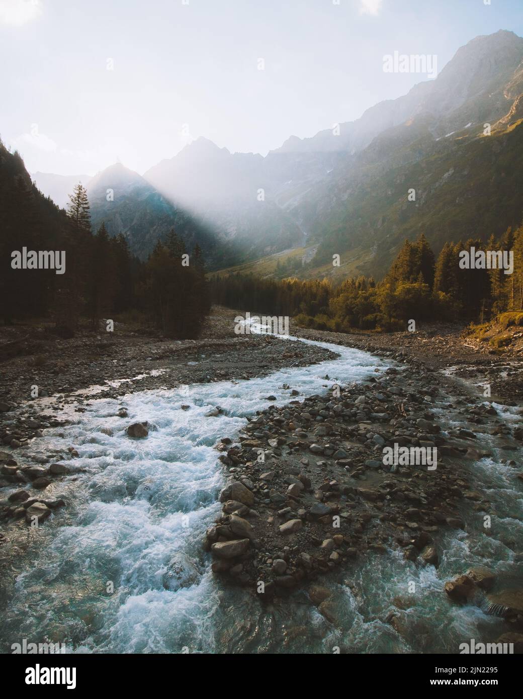 A vertical shot of a river flowing through forested mountains Stock ...