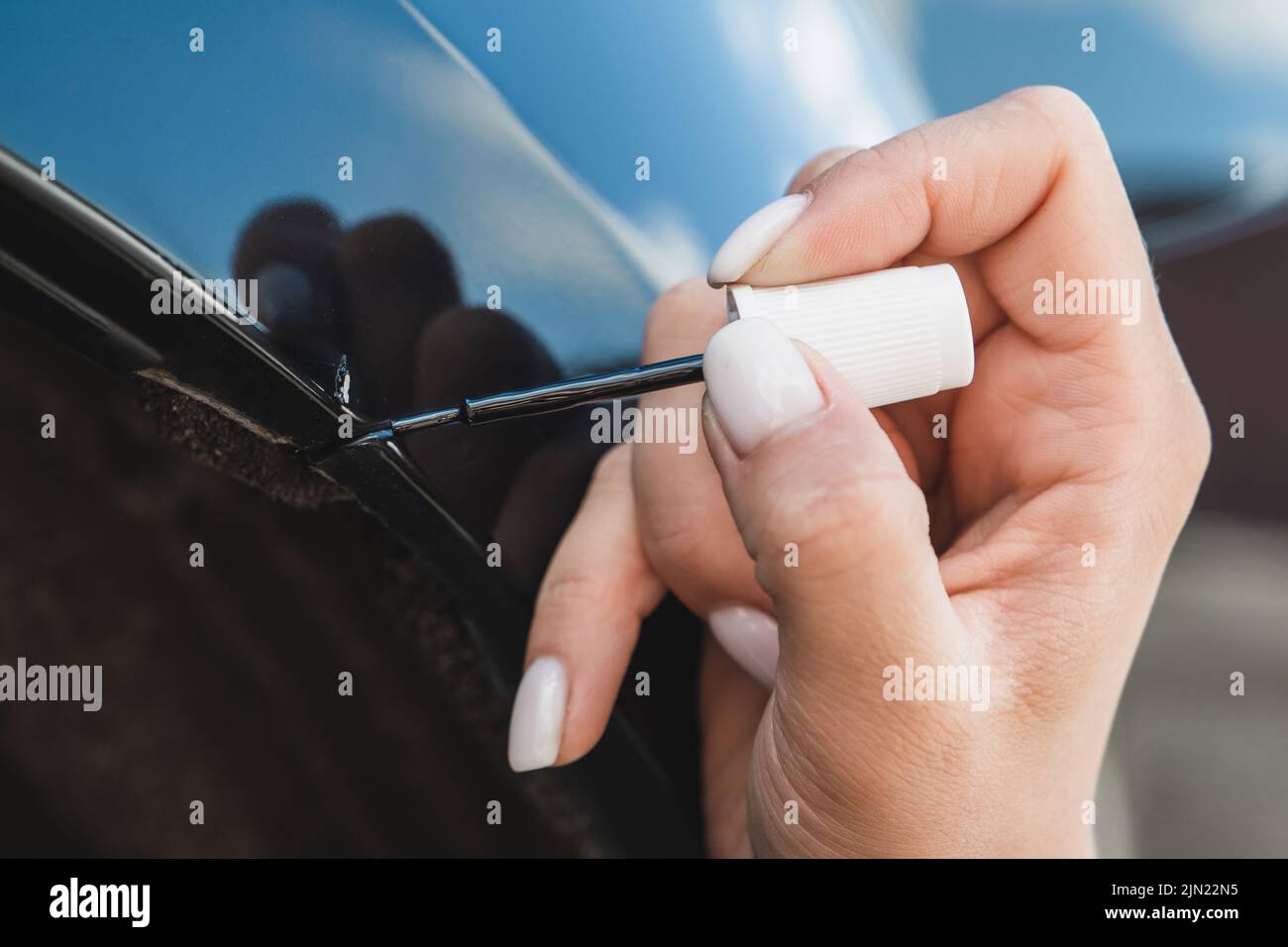 Touching up a body car with a small brush by a young woman Stock Photo
