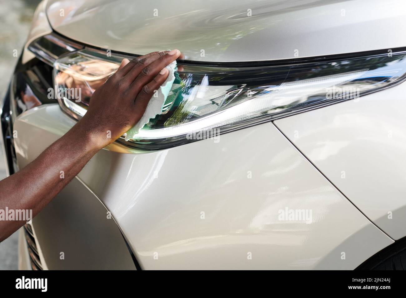Hand of car owner wiping oxidized headlights to take off fog without