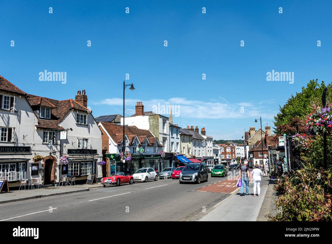 Dorking, Surrey Hills, London UK, July 07 2022, High Street Row Of Shops With Cars and Pedestrian Walking Under Blue Sky Stock Photo