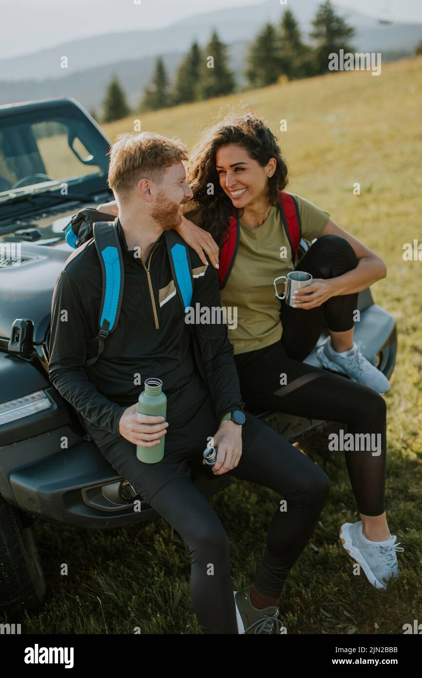 Handsome young couple relaxing on a terrain vehicle hood at countryside Stock Photo
