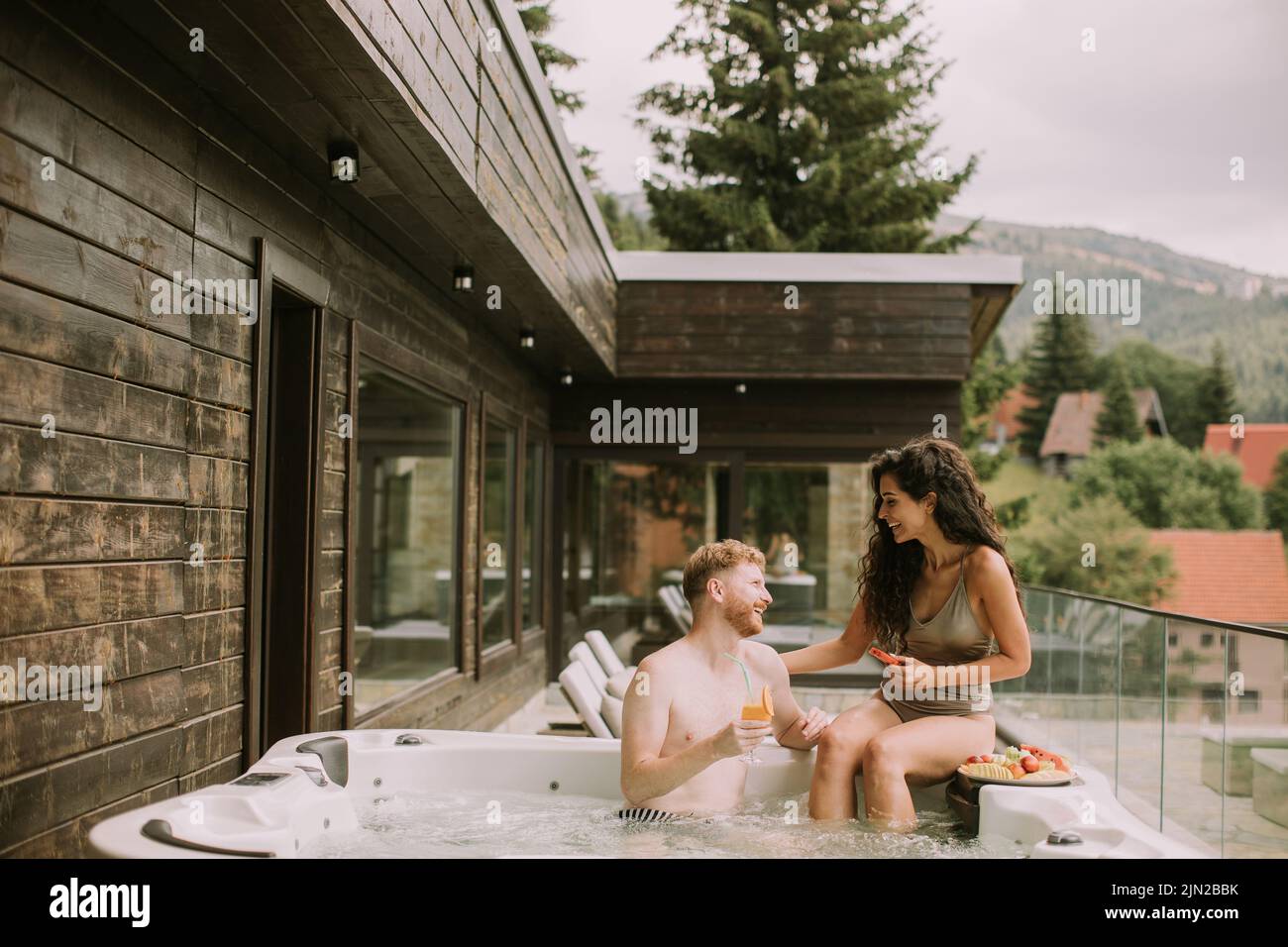Attractive young couple enjoying in outdoor hot tub on vacation Stock Photo