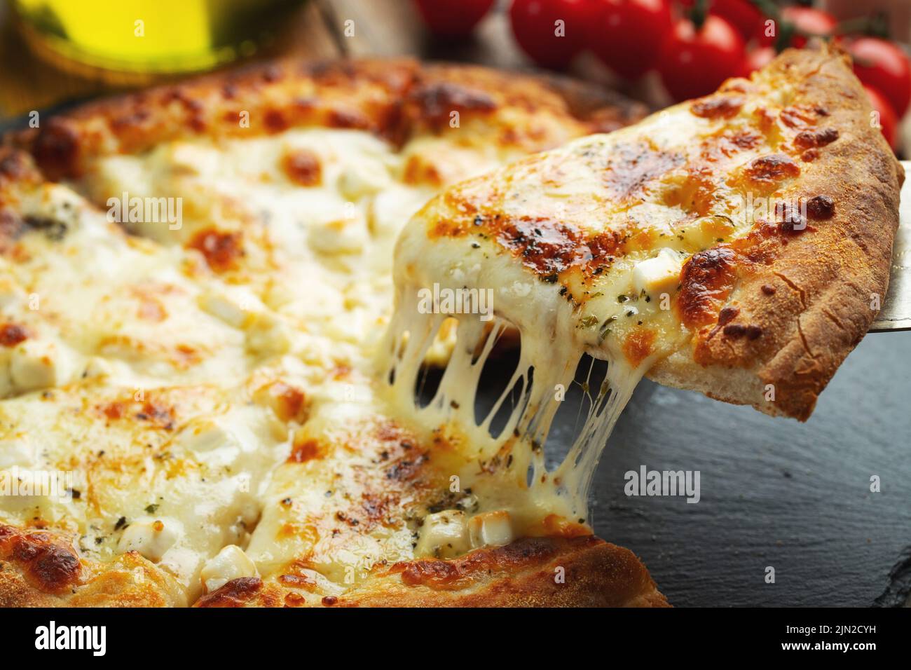A slice of hot Italian pizza with stretching cheese. Pizza four cheeses