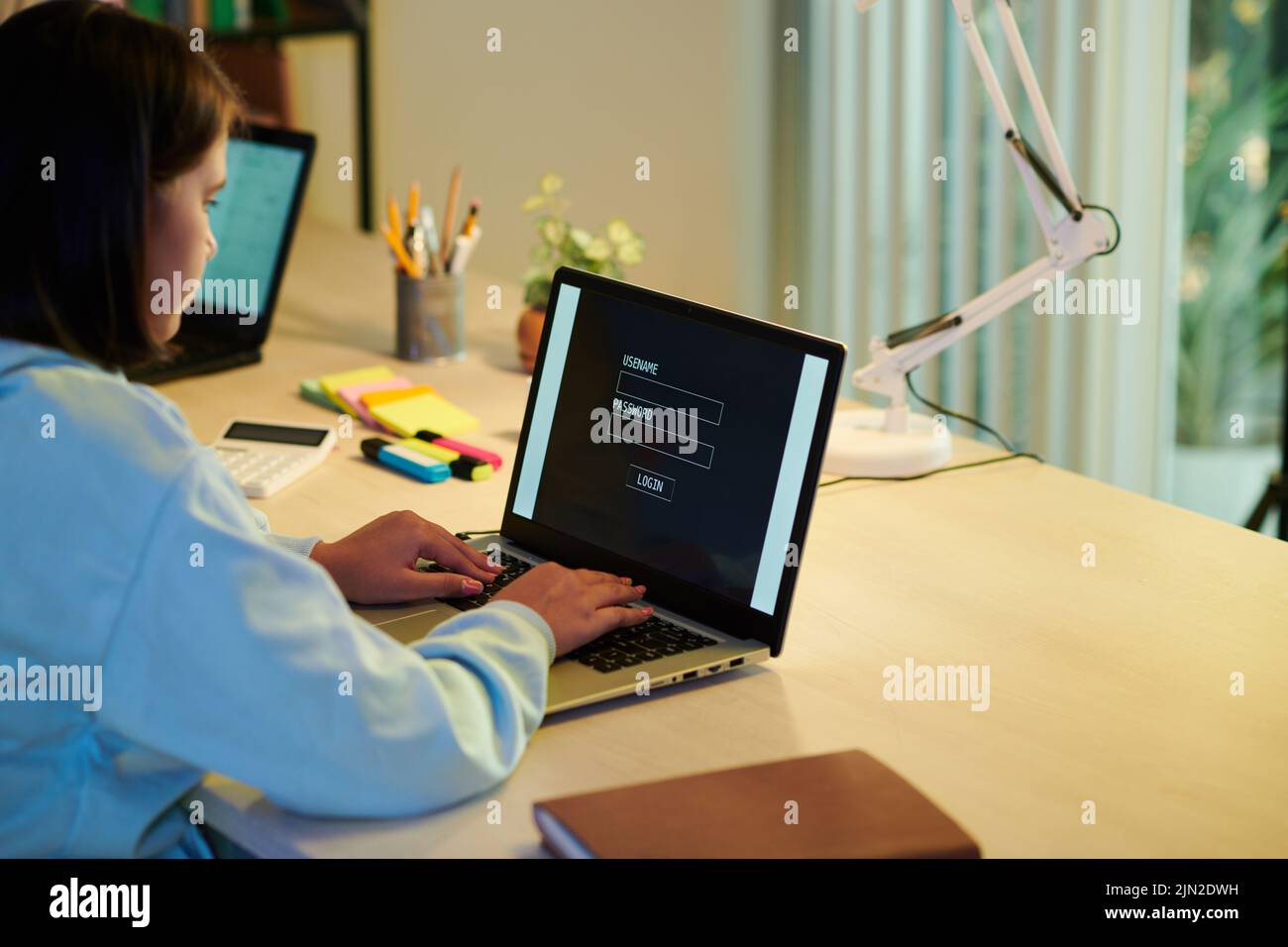 Schoolgirl entering username and password to log in school website Stock Photo