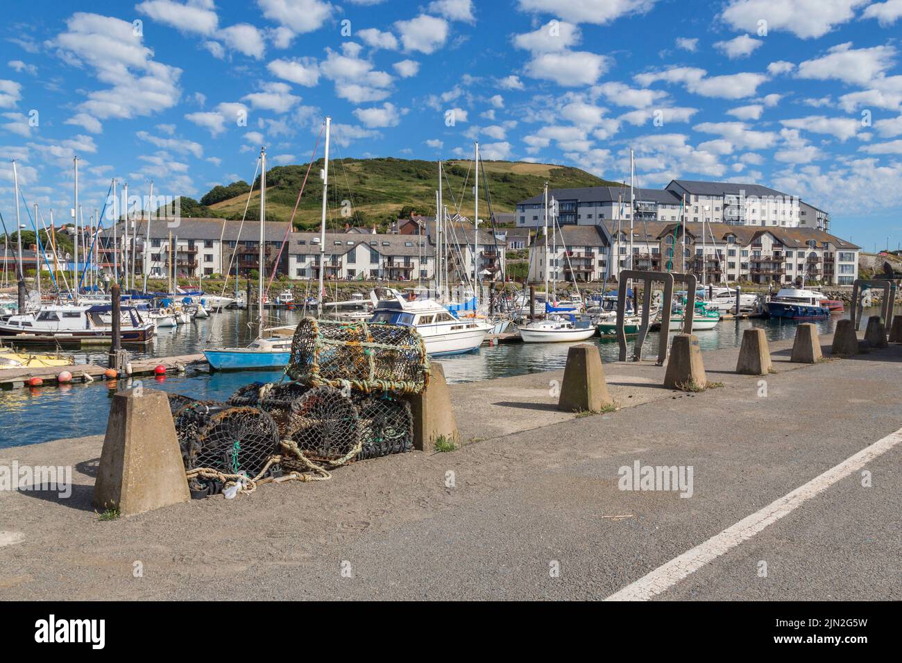 Lobster pots and sailing boats along the quay at Aberystwyth marina. Stock Photo