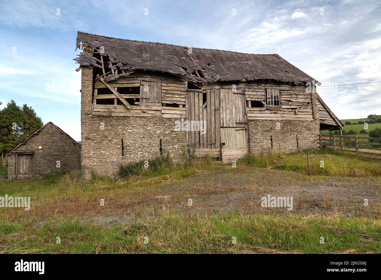 An old barn and outbuilding stand weathered and abandoned in a field. Stock Photo