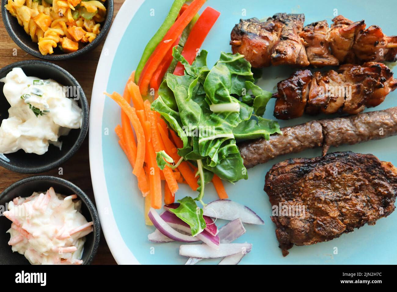 Plate with braai meat and salads. Including chicken kebabs, boerewors