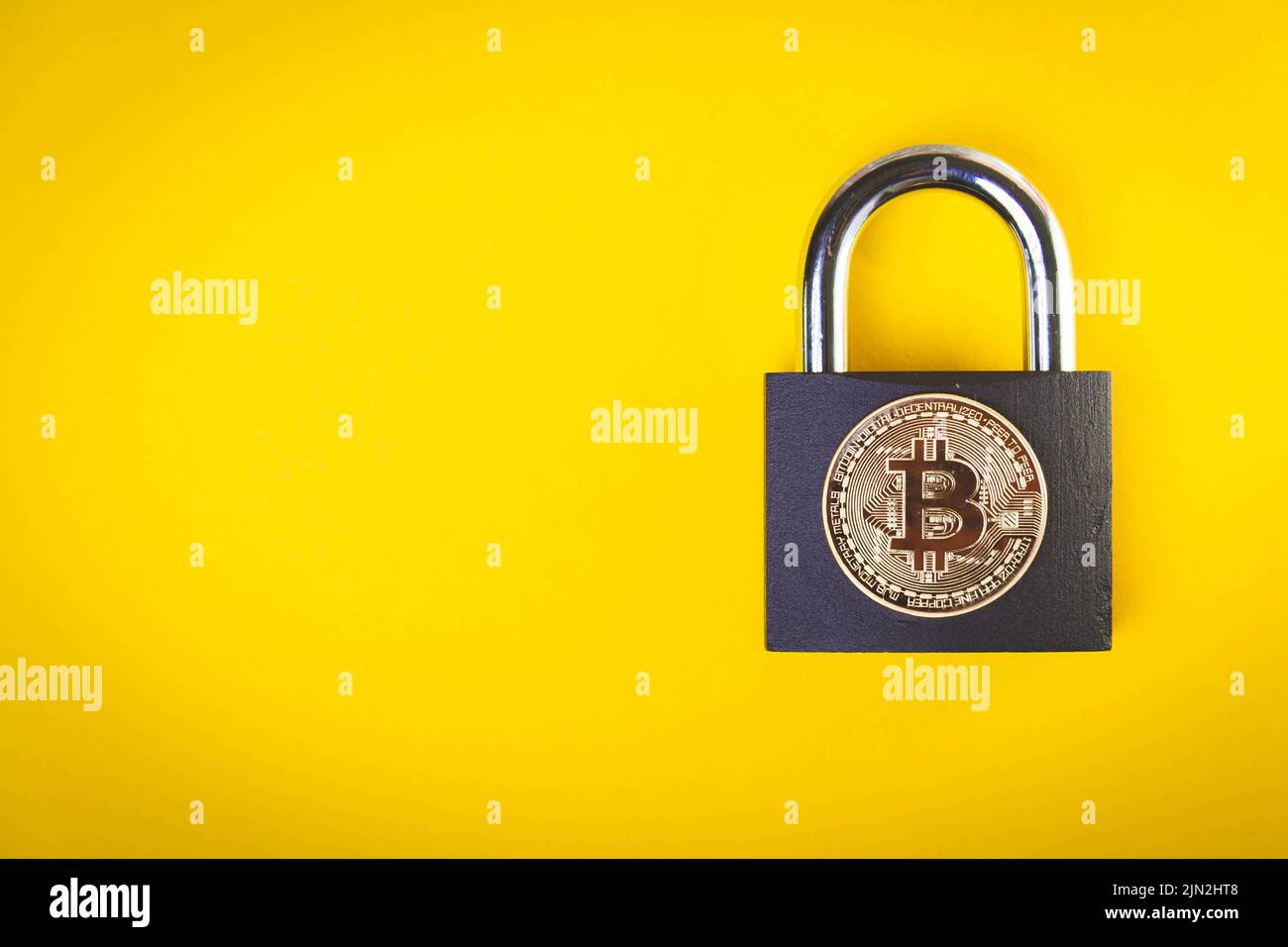 Cryptocurrency is banned. bitcoin transfer ban. Rate drop. Bitcoin coin and padlock on yellow background. Stock Photo