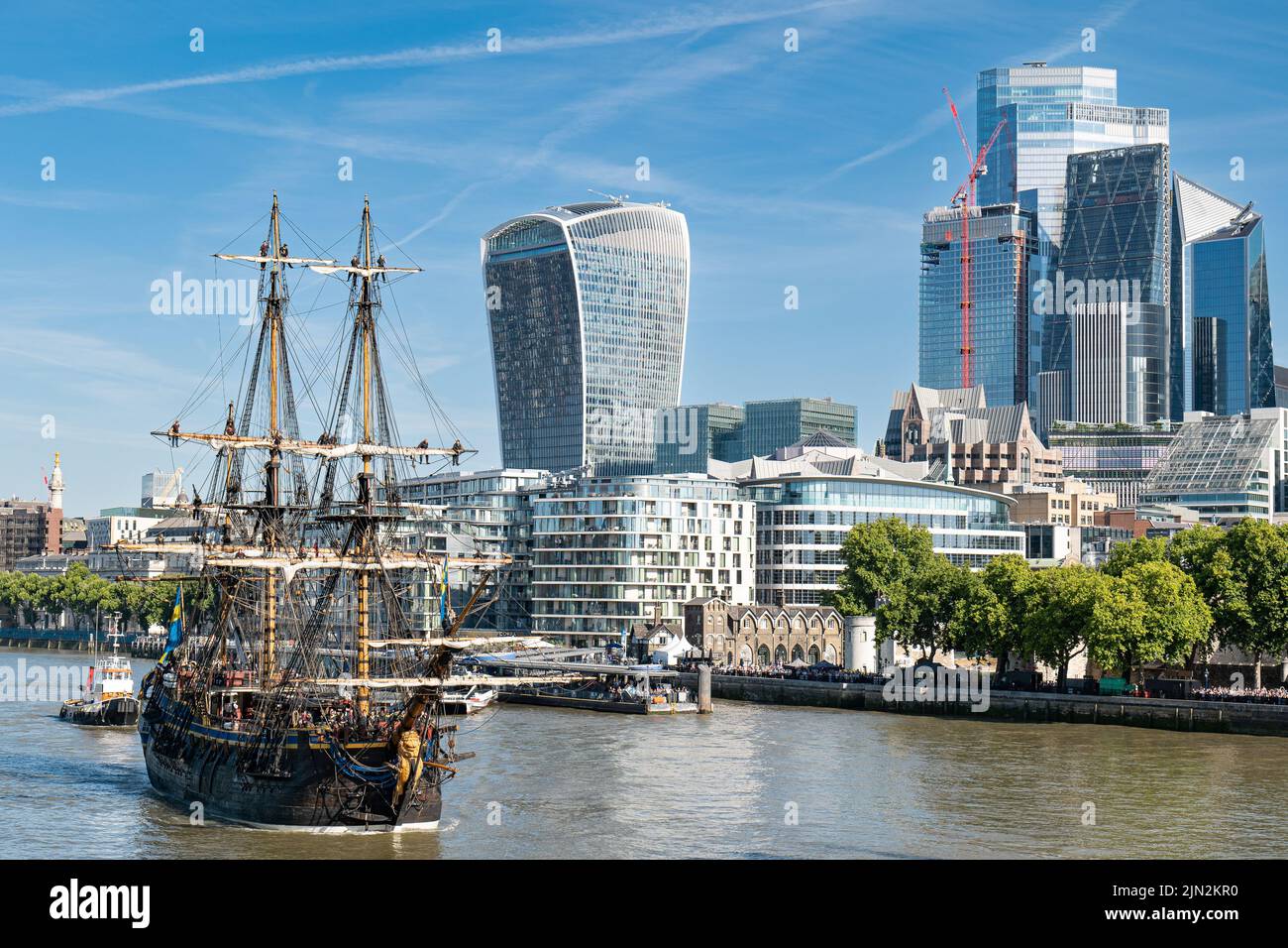 Contrast old and new: 18th century (replica) sailing ship Gothenborg approaching Tower Bridge, crew in the rigging, overlooked by London skyscrapers. Stock Photo
