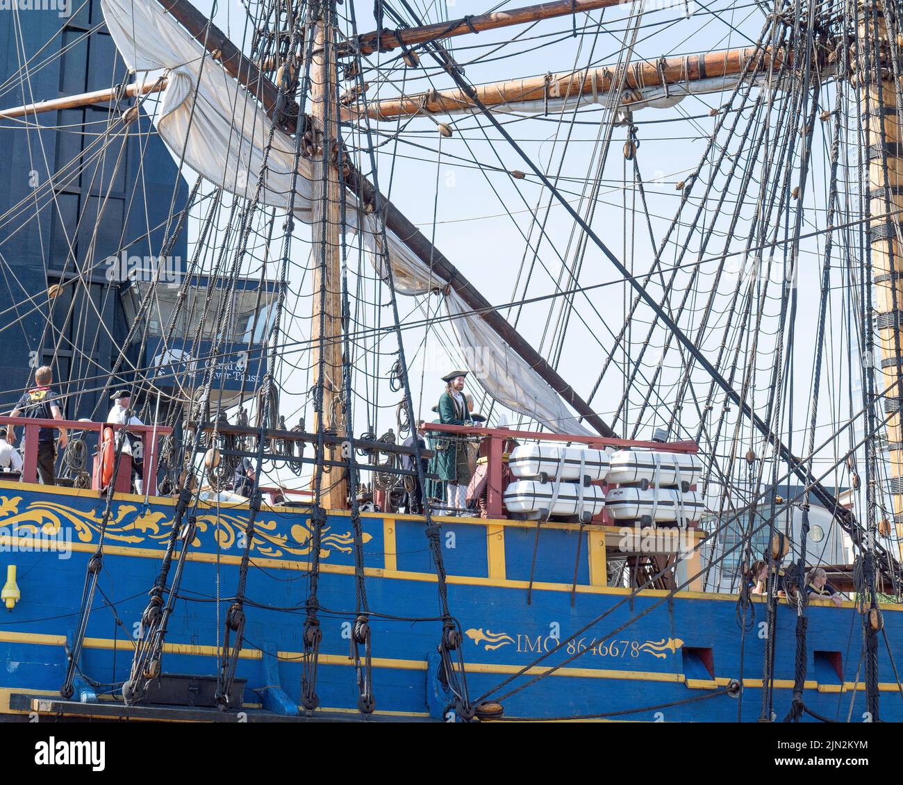 Crew of Swedish tall ship Gotheborg, some in 18th century maritime uniform, keep a lookout as she passes under Blue Bridge to her Thames Quay berth. Stock Photo