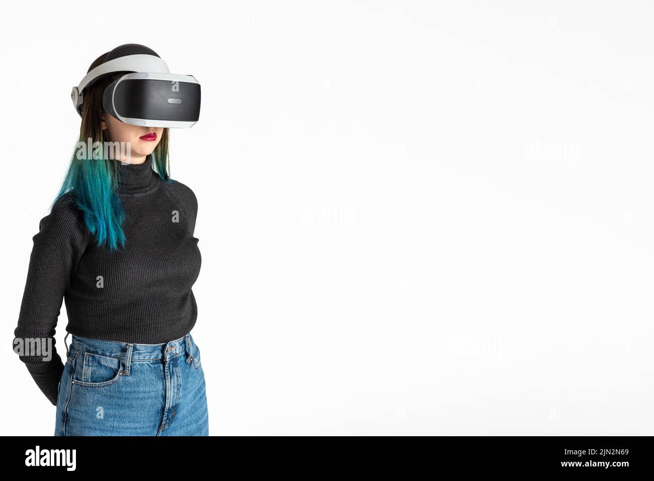 A teenager girl in a vr helmet plays in the virtual universe isolated on a white background, vertical frame. The concept of the virtual universe. Life Stock Photo