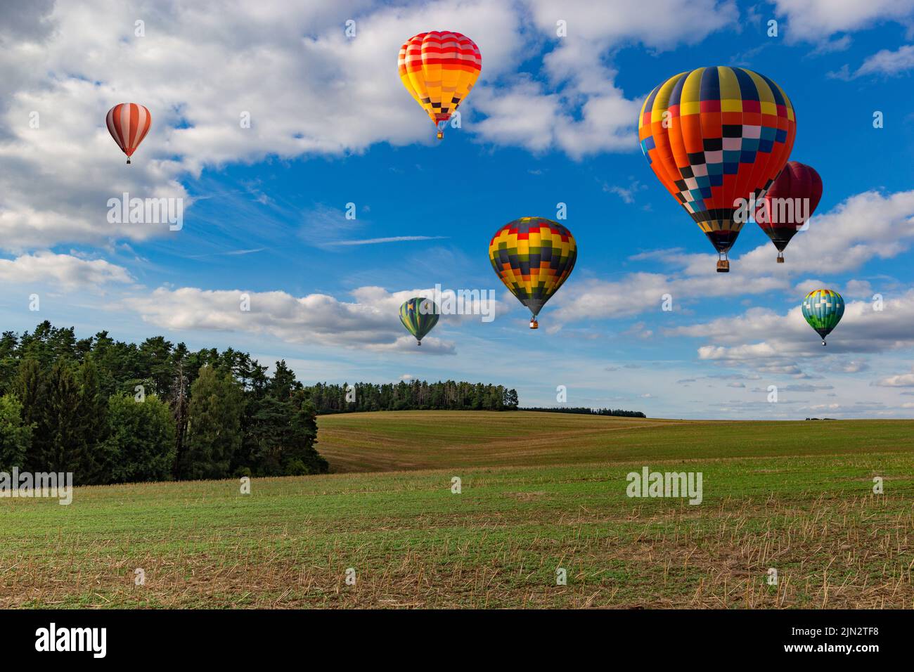 Multicolored hot air balloons fly in blue sky with white clouds over ...