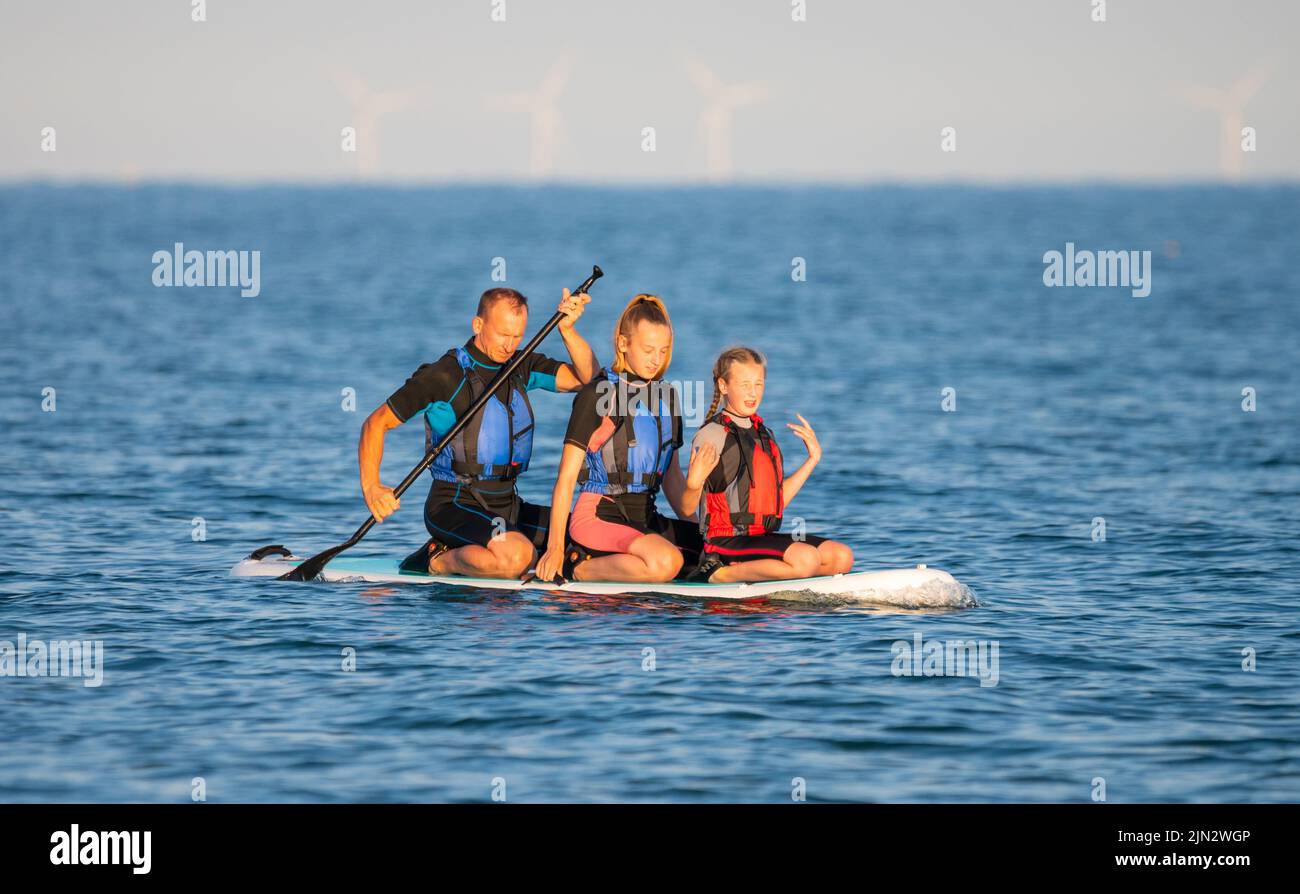 Littlehampton, West Sussex, UK. Monday 8th August 2022. A group of people take a paddleboard ride on the sea late this evening, as the heatwave continues on the south coast. Credit: Geoff Smith/Alamy Live News Stock Photo