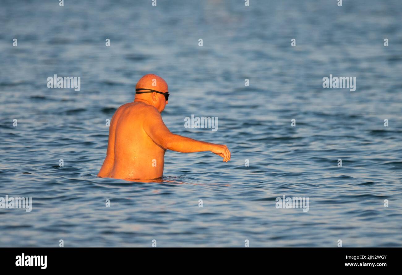 Littlehampton, West Sussex, UK. Monday 8th August 2022. A swimmer cools off in the sea late this evening as the heatwave continues on the south coast. Credit: Geoff Smith/Alamy Live News Stock Photo